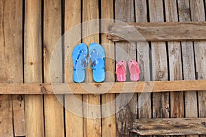 Two pairs of flip flops on a wooden wall waiting for summer vacation