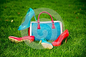 Two pairs of green and red shoes and bag lay on the grass