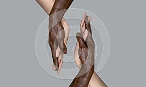 Two pairs of hands: the black male and white female hands touch palms, holding each other. The concept of interracial friendship,