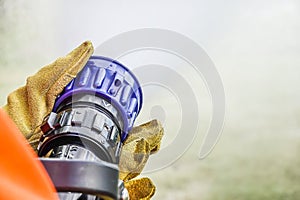 Two pairs of hands holding the handle on the end of a fire fighters water hose spraying water during practice