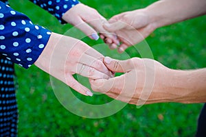 Two pairs of hands in love tenderly hold together on green grass background