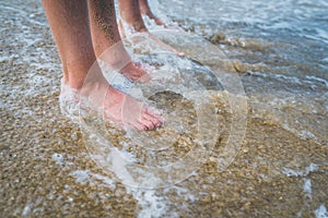 Two pairs of kids feet on the sand in the water .Family on vacations.