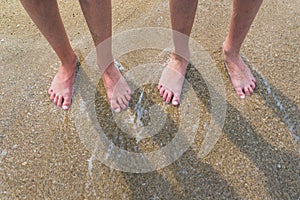 Two pairs of kids feet on the sand in the water .Family on vacations.