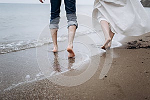 Two pairs of legs of lovers walk on the sand on the seashore.