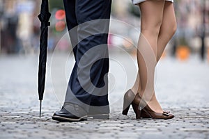 Two pairs of legs of man and woman in classic shoes on background of urban sidewalk