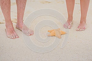 Two pairs of legs and starfish on white sand