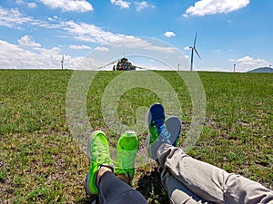 Two pairs of legs with whoes on lying on a vast pasture in Xilinhot in Inner Mongolia. In the back there is a heap of stones