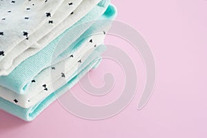 Two pairs of mint blue and two pairs of white in black speckled cotton socks on a pink background.