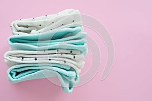 Two pairs of mint blue and two pairs of white in black speckled cotton socks on a pink background.