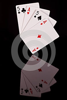 Two pairs, a pair of aces, and a pair of fives, on a black background, poker