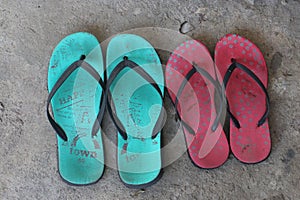 Two pairs of slippers on the cement floor. Two house slippers for men and women