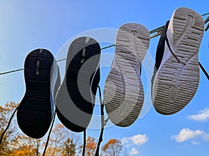 Two pairs of sneakers are drying on a clothesline against a blue sky