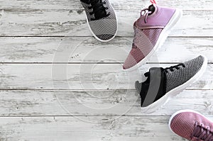 Two pairs of sneakers violet, black and white on wooden backg