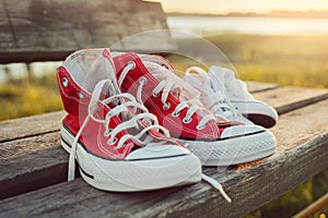 Two pairs of sports shoes on a bench at sunset