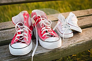 Two pairs of sports shoes on a bench at sunset