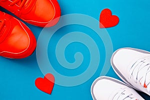 Two pairs of sports shoes and a pair of red hearts on a blue background