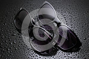 two pairs sunglasses with water drops