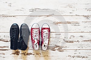 Two pairs of trainers, red and black, on wooden floor top view