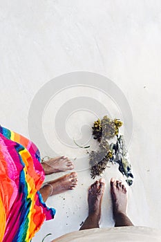 Two pairs of women`s feet on a sandy beach with seaweed