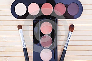 Two palettes with beige,pink,black,white eye shadows and two makeup brushes on a light background.Selective focus.Top view.Concept
