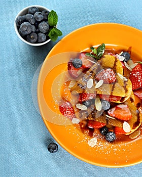 Two pancakes hearts with strawberry, blueberries and almond slivers