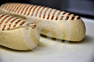 Two panini rolls lying on a white chopping board