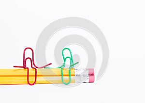 Two paper clips talking, having conversation while sitting on a pile of pencils. Miniature school life and back to school concept