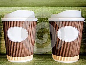 Two paper coffee cups with green background