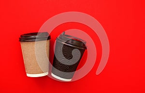 Two paper coffee cups on red background. Copy space for text