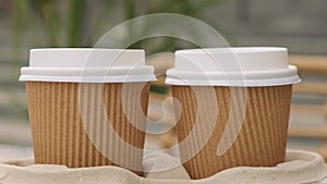 Two paper cups with lid for tea to go. Coffee take away on the table. Take-out coffees with brown paper cup holder