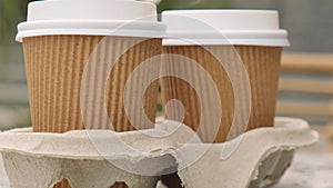 Two paper cups with lid for tea to go. Coffee take away on the table. Take-out coffees with brown paper cup holder