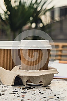 Two paper cups with lid for tea to go. Coffee take away on the table. Take-out coffees with brown paper cup holder