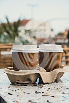 Two paper cups with lid for tea to go. Coffee take away on the table. Take-out coffees with brown paper cup holder