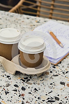 Two paper cups with lid for tea to go. Coffee take away on the table. Take-out coffees with brown paper cup holder