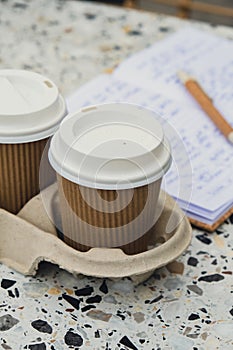 Two paper cups with lid for tea to go. Coffee take away on the table. Take-out coffees with brown paper cup holder