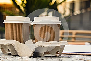 Two paper cups with lid for tea to go. Coffee take away on the table. Take-out coffees with brown paper cup holder