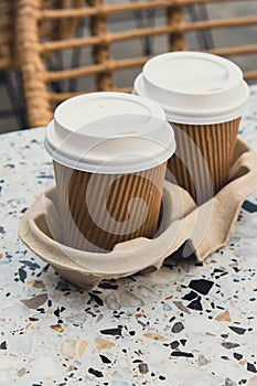 Two paper cups with lid for tea to go. Coffee take away on the table. Take-out coffees with brown paper cup holder