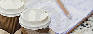 Two paper cups with lid for tea to go. Coffee take away on the table. Take-out coffees with brown paper cup holder