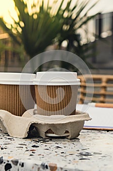 Two paper cups with lid for tea to go. Coffee take away on the table. Take-out coffees with brown paper cup holder