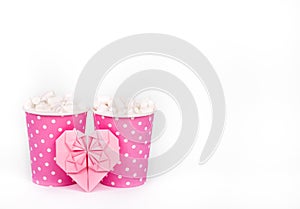 Two paper cups and valentine on white background. Cocoa, marshmallow and paper heart. Romantic concept. St. Valentine`s Day.