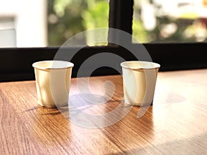 Two paper cups on a wooden table in a coffee shop, stock photo