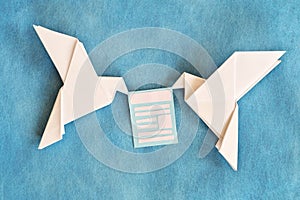 Two paper dove origami carrying email newsletter document in blue background.
