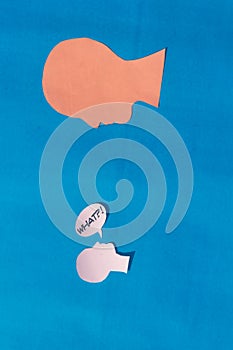 Two Paper Human face with what Question Mark on speech bubble isolated on blue background. Conceptual images showing Big Questions