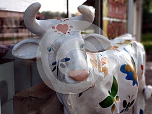 Two papier mache cow statues with painted flowers in front of the butchers shop