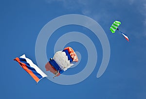 Two parachutists gliding with russian flags on blue sky background