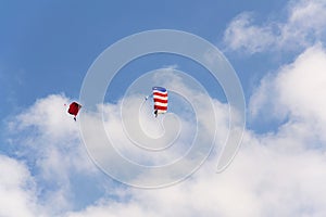 Two parachutists skydiving with colorful parachute clouds blue sky background