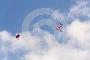 Two parachutists skydiving with colorful parachute clouds blue sky background