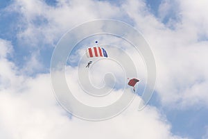 Two parachutists skydiving with colorful parachute clouds blue sky background