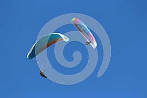 Two paragliders in blue sky