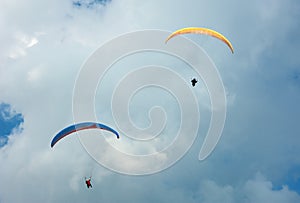 Two paragliders flying in the blue sky.